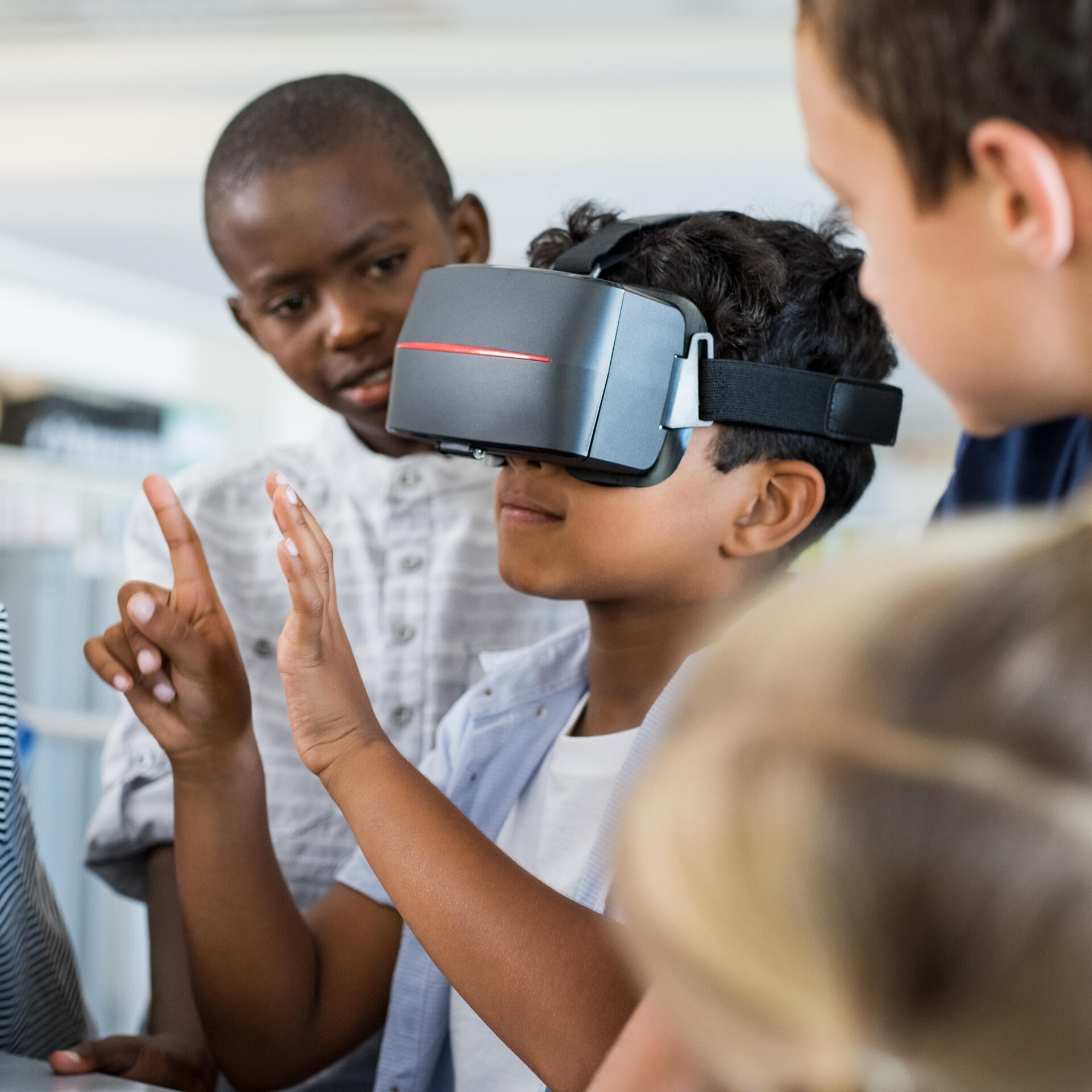 Kids playing with Virtual Reality equipment with one holding up a number of fingers.