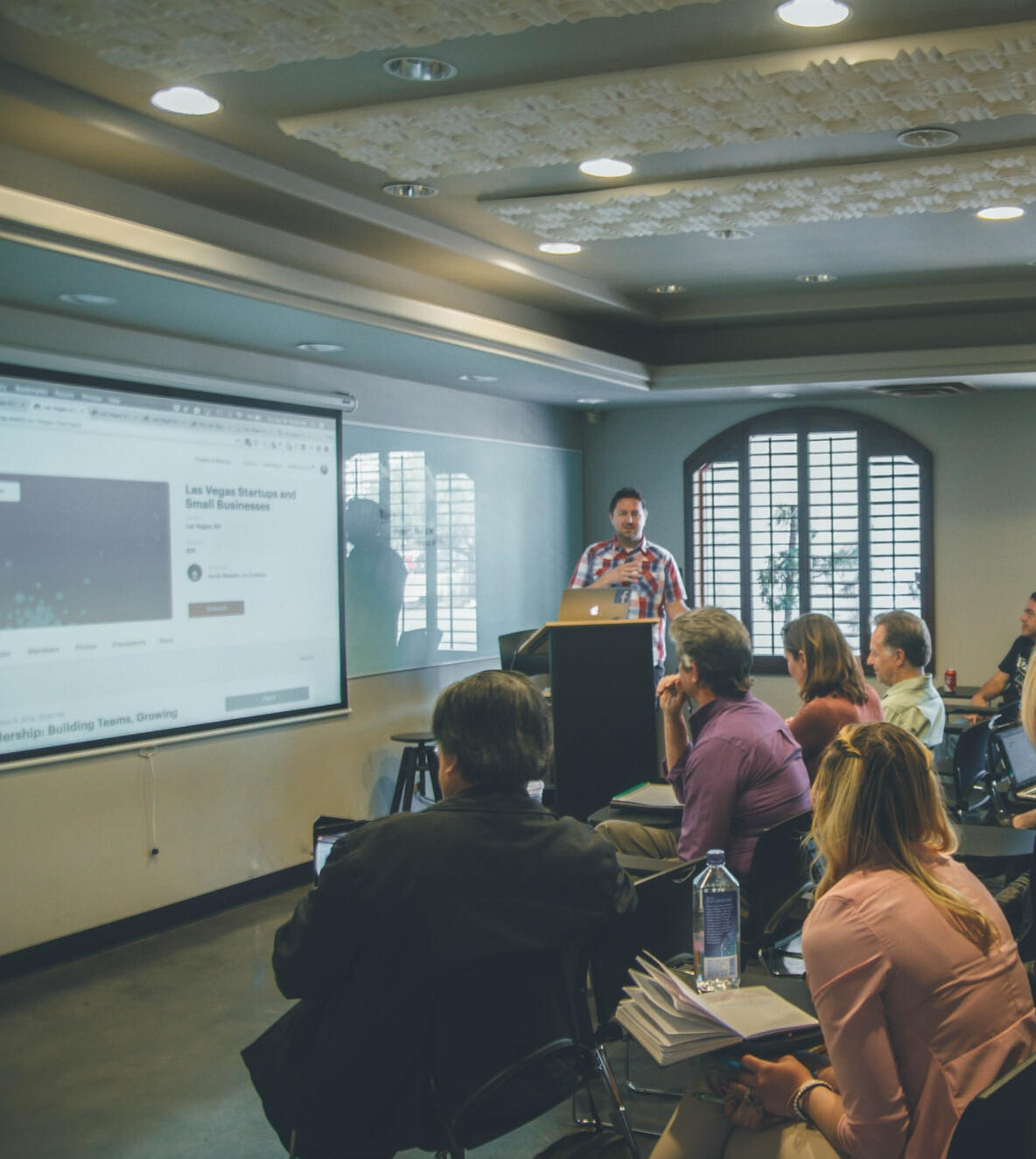 Training taking place with a speaker presenting in a room full of seated people.